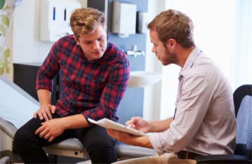 An image showing a man talking with a therapist at an alcohol addiction clinic