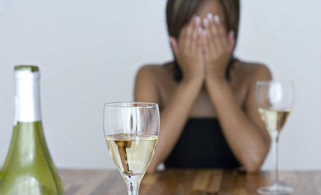 Image showing a woman sitting behind glasses of champagne, in desperation about her alcohol abuse